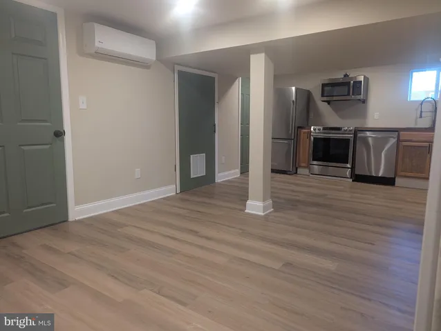 an empty room with wooden floor and a kitchen view