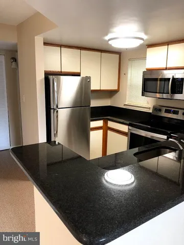 a kitchen with stainless steel appliances a refrigerator a sink a stove and a sink