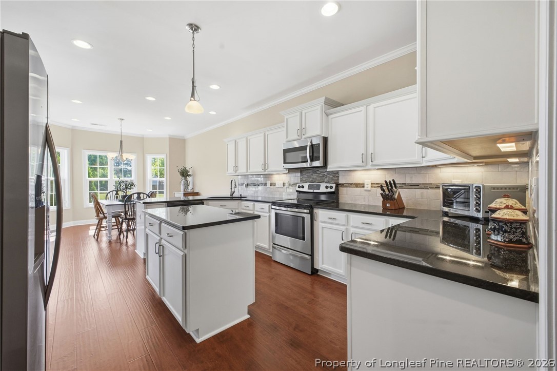 2589 June Johnson Road Raeford, NC 28376 - Photo 10 of 49 a kitchen with stainless steel appliances granite countertop a refrigerator a stove top oven a sink dishwasher a dining table and chairs with wooden floor