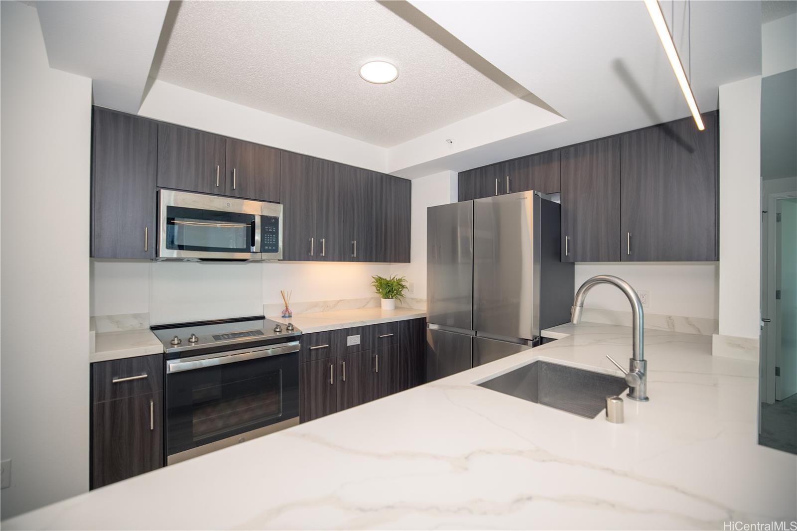 615 Keawe Street, Unit 2408 Honolulu, HI 96813 - Photo 3 of 5 a kitchen with granite countertop a refrigerator and a stove top oven