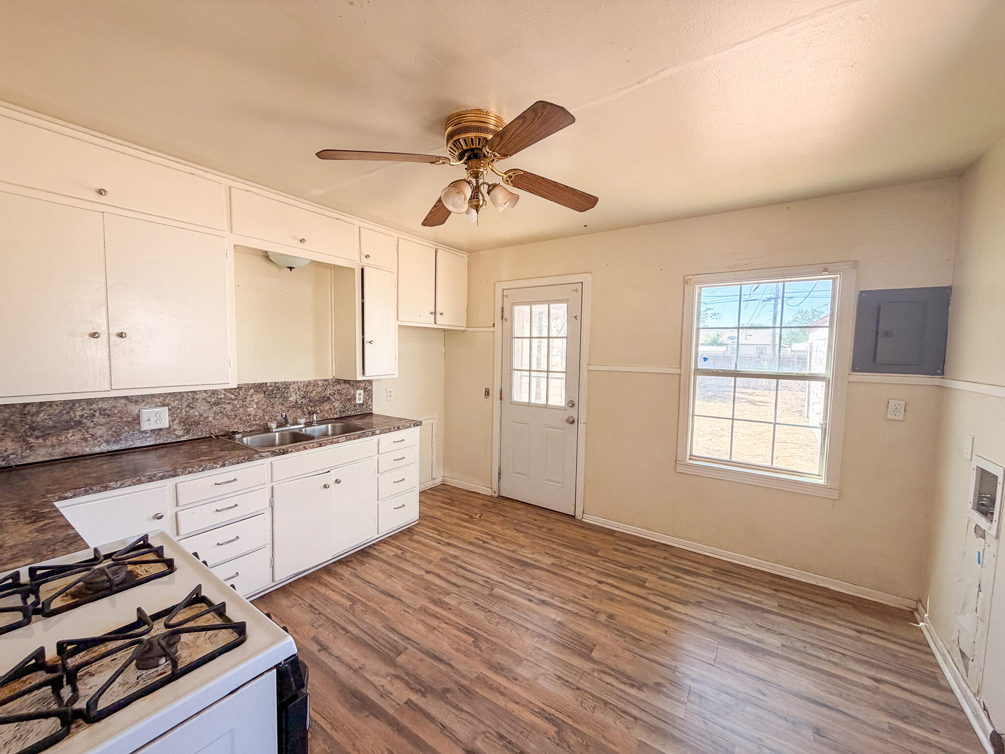 3207 Amherst Street Lubbock, TX 79415 - Photo 4 of 16 a kitchen with granite countertop a stove a sink and wooden floor
