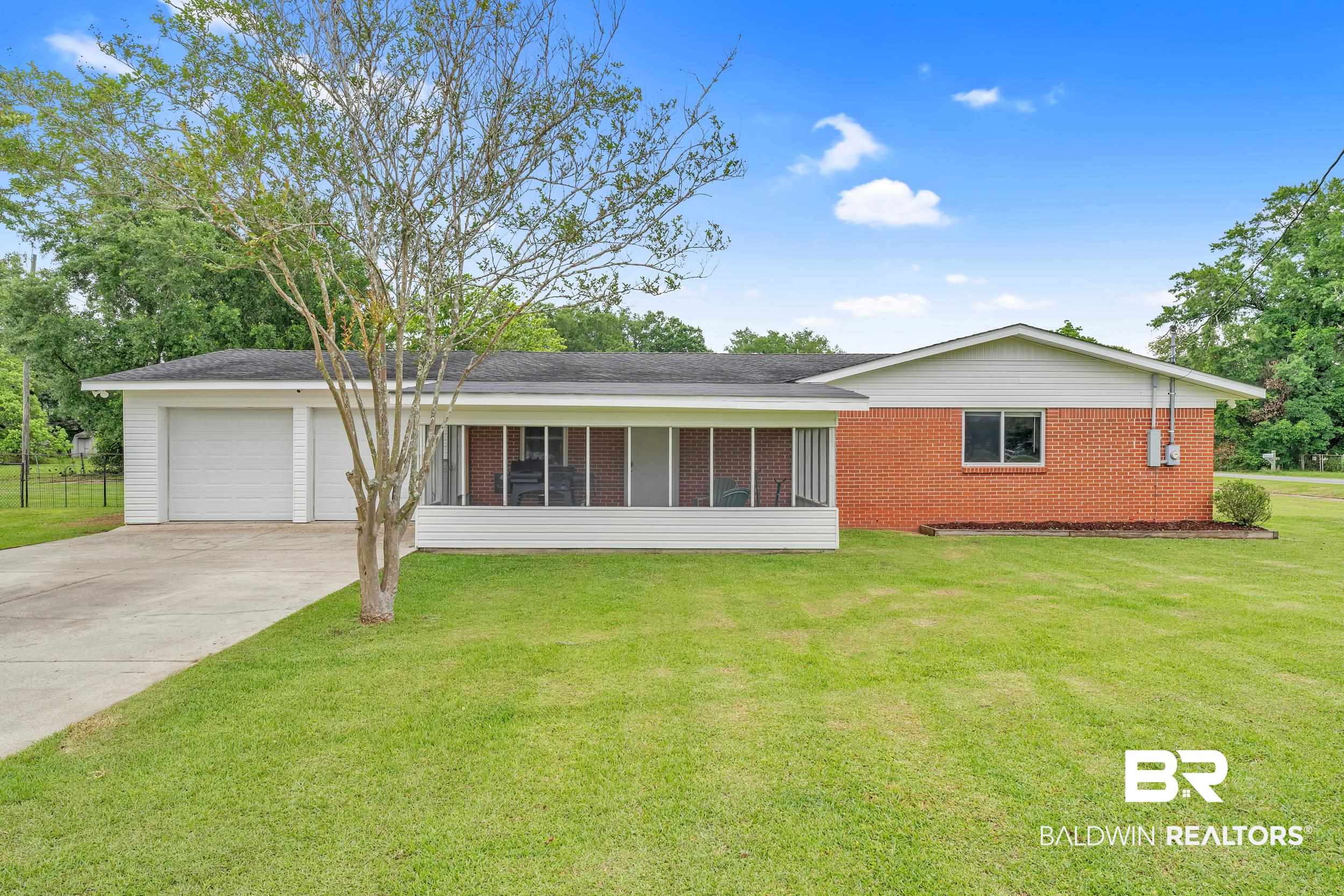 206 West Jackson Avenue Summerdale, AL 36580 - Photo 1 of 37 View of front of home featuring concrete driveway, brick siding, a front lawn, and a garage