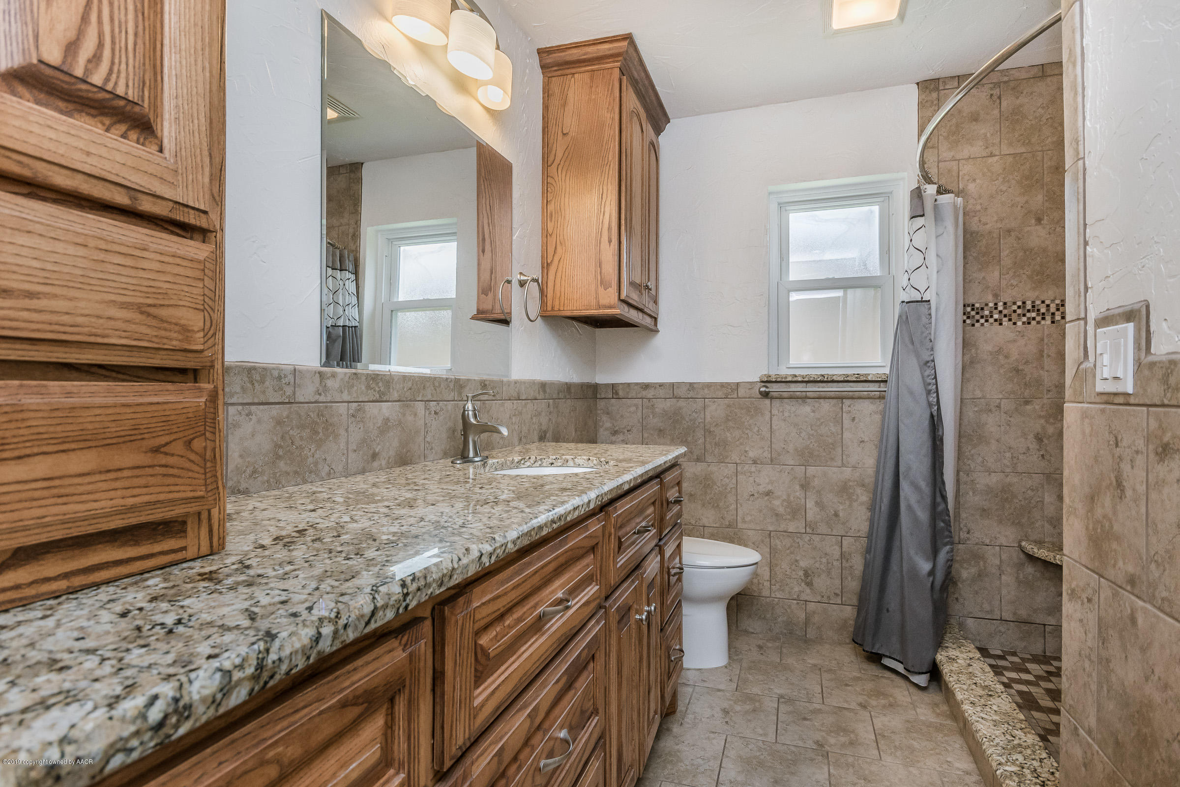 5145 McCarty Boulevard Amarillo, TX 79110 - Photo 15 of 21 a bathroom with a granite countertop sink a toilet and shower