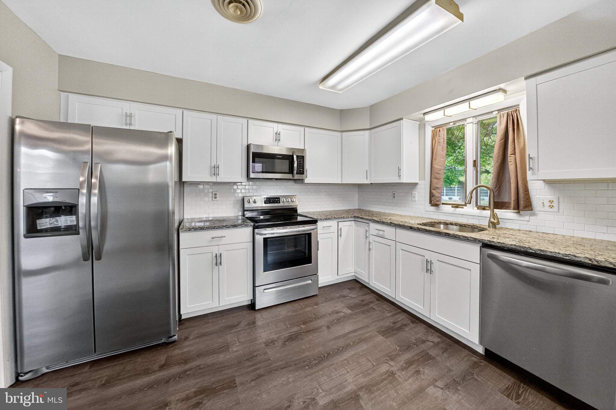 7043 Basswood Road Frederick, MD 21703 - Photo 10 of 34 a kitchen with kitchen island granite countertop a refrigerator oven a sink and a window