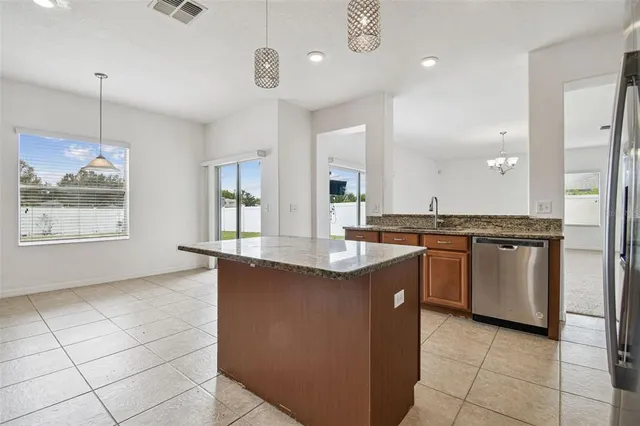 a kitchen with kitchen island granite countertop a sink a counter top space appliances and cabinets