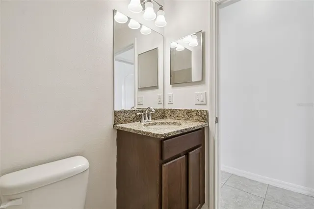 a bathroom with a granite countertop sink a toilet and a mirror