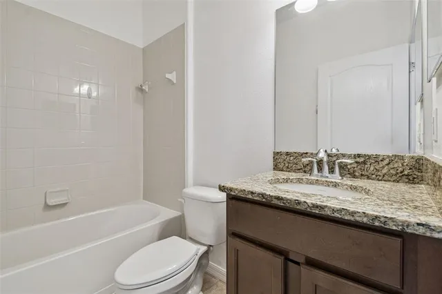 a bathroom with a granite countertop toilet sink and mirror