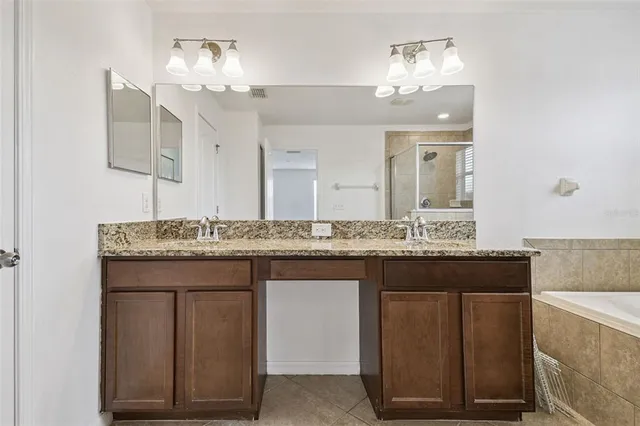 a bathroom with a granite countertop sink a large mirror and a wooden floors