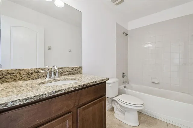 a bathroom with a granite countertop sink a toilet and shower