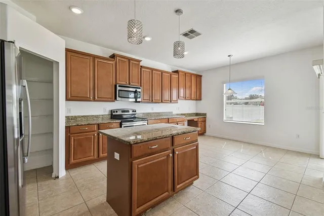 a kitchen with stainless steel appliances granite countertop a stove top oven a sink a refrigerator and a granite counter tops