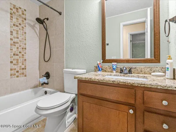 a bathroom with a granite countertop toilet sink and mirror