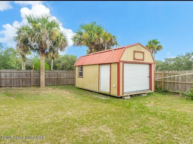 a view of a backyard with brick wall and potted plants
