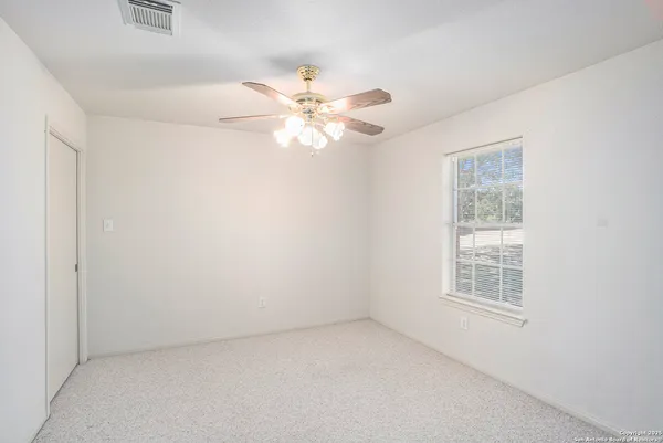 an empty room with a window and a fan