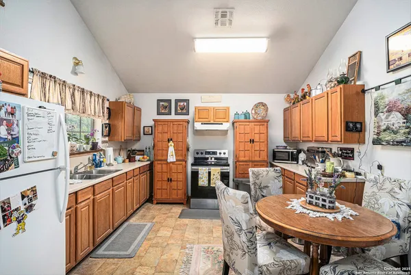 a kitchen with stainless steel appliances kitchen island granite countertop a table chairs and a refrigerator