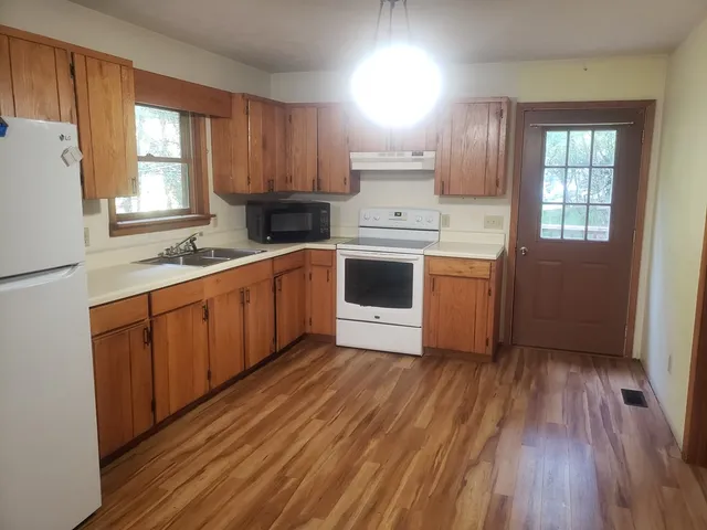 a kitchen with granite countertop wooden cabinets and white appliances