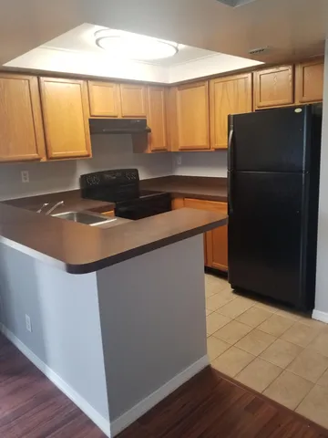 a kitchen with granite countertop a refrigerator and a stove top oven