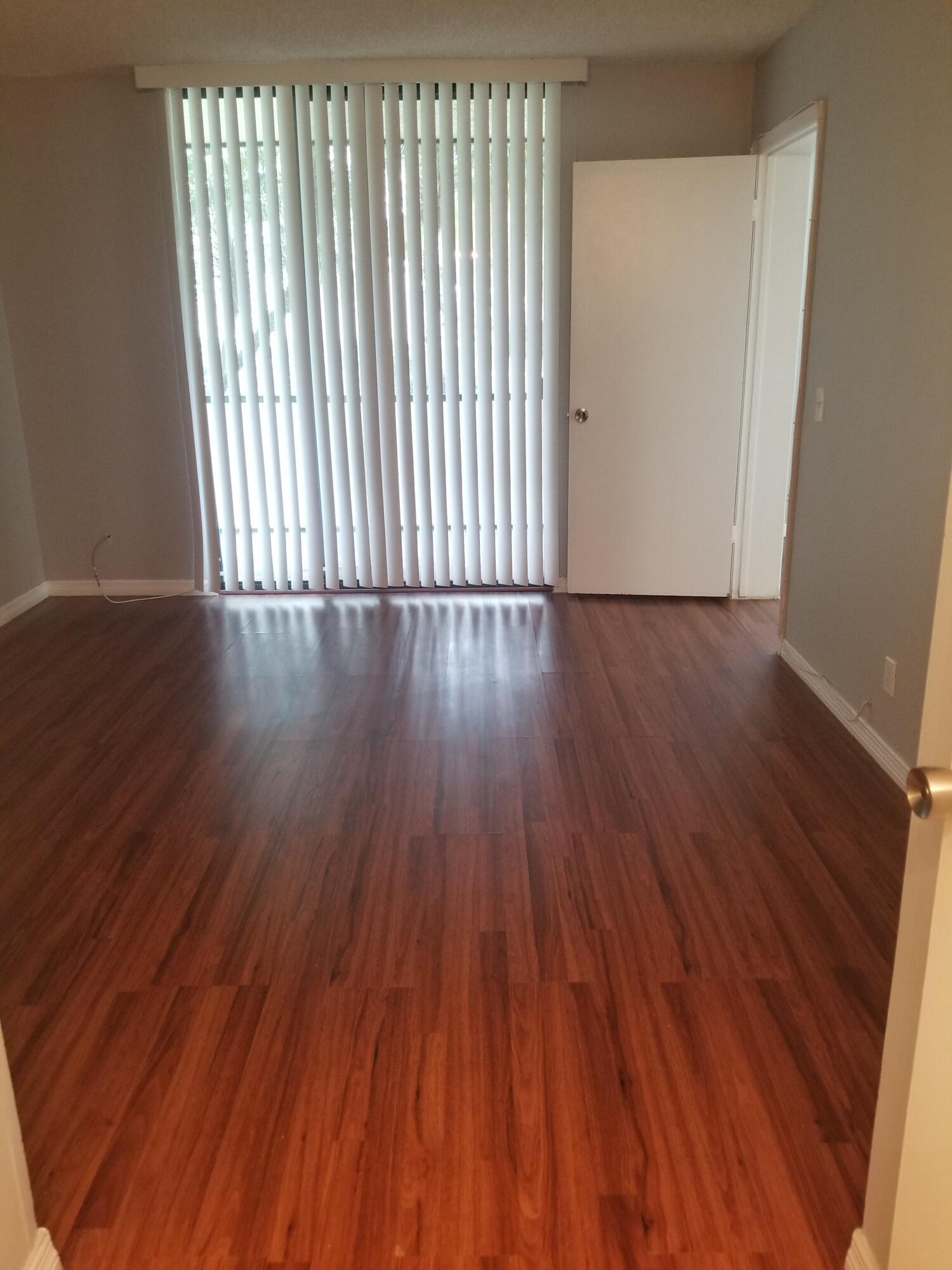 718 Executive Center Drive, Unit 19 West Palm Beach, FL 33401 - Photo 4 of 20 an empty room with wooden floor and windows