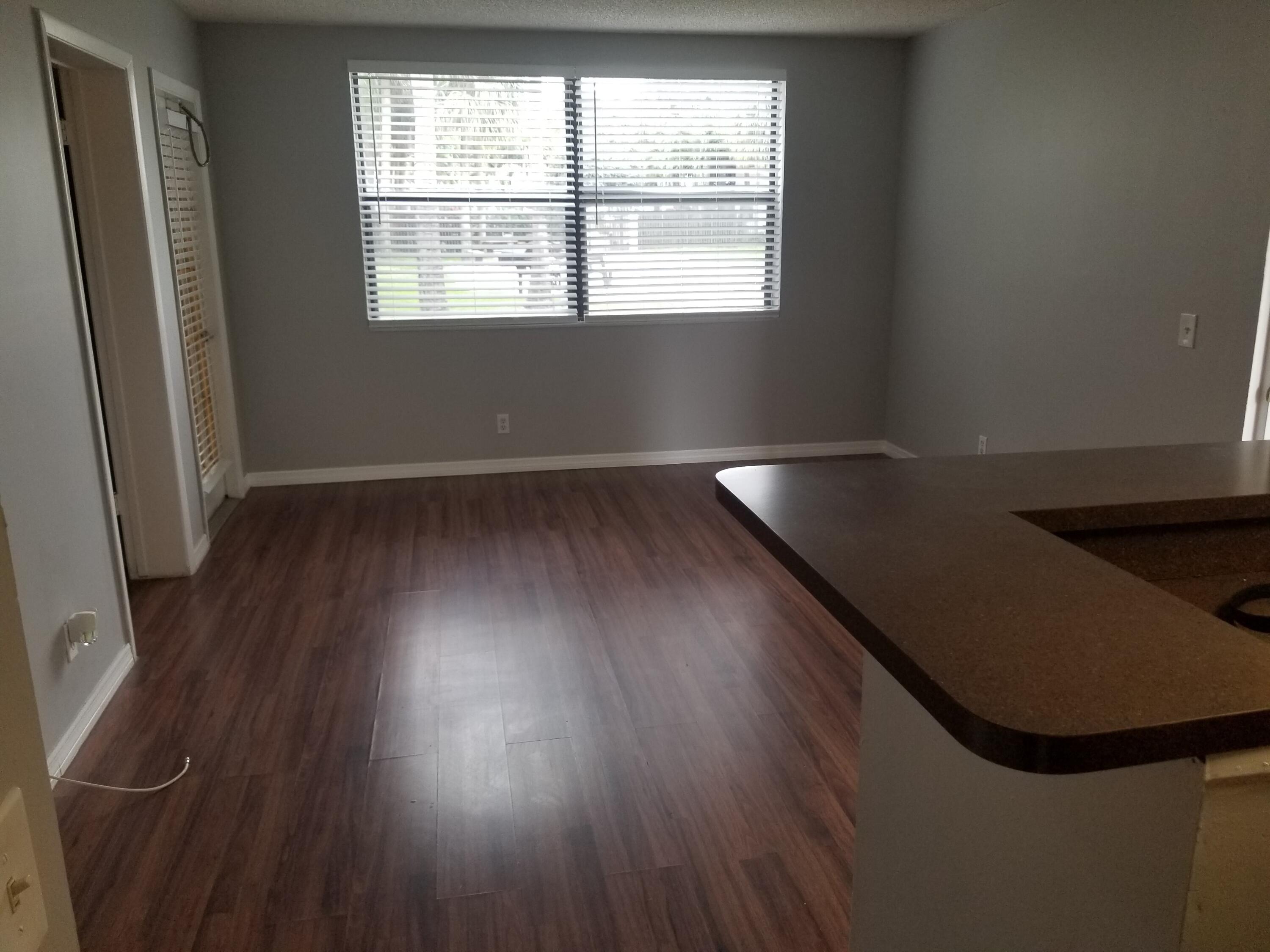718 Executive Center Drive, Unit 19 West Palm Beach, FL 33401 - Photo 6 of 20 an empty room with wooden floor and windows