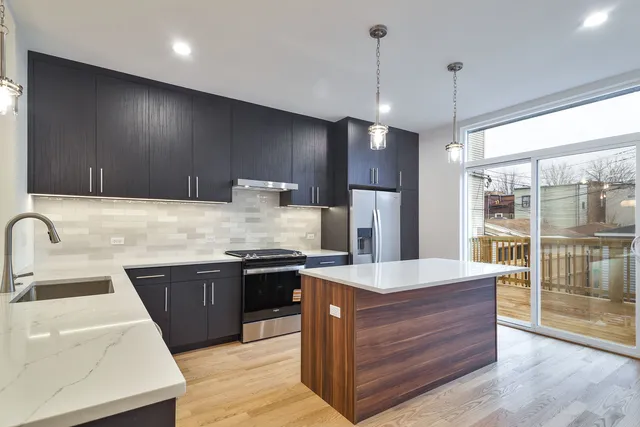 a large kitchen with stainless steel appliances granite countertop a sink a stove and a refrigerator