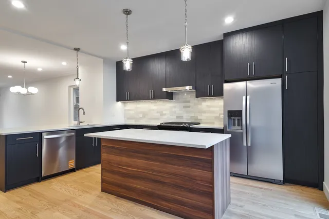 a kitchen with kitchen island a counter space a sink appliances and cabinets