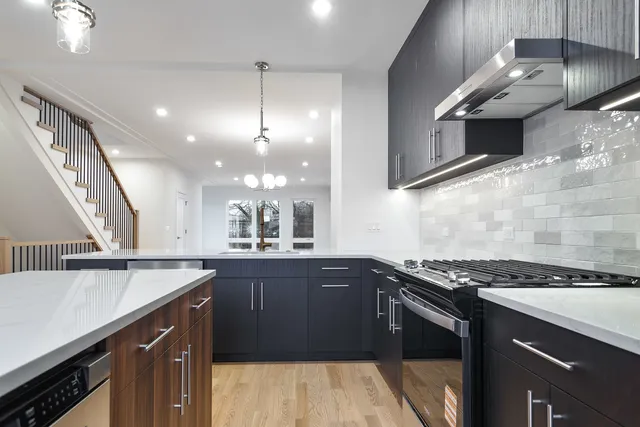 a kitchen with stainless steel appliances granite countertop a sink a stove and a wooden floors