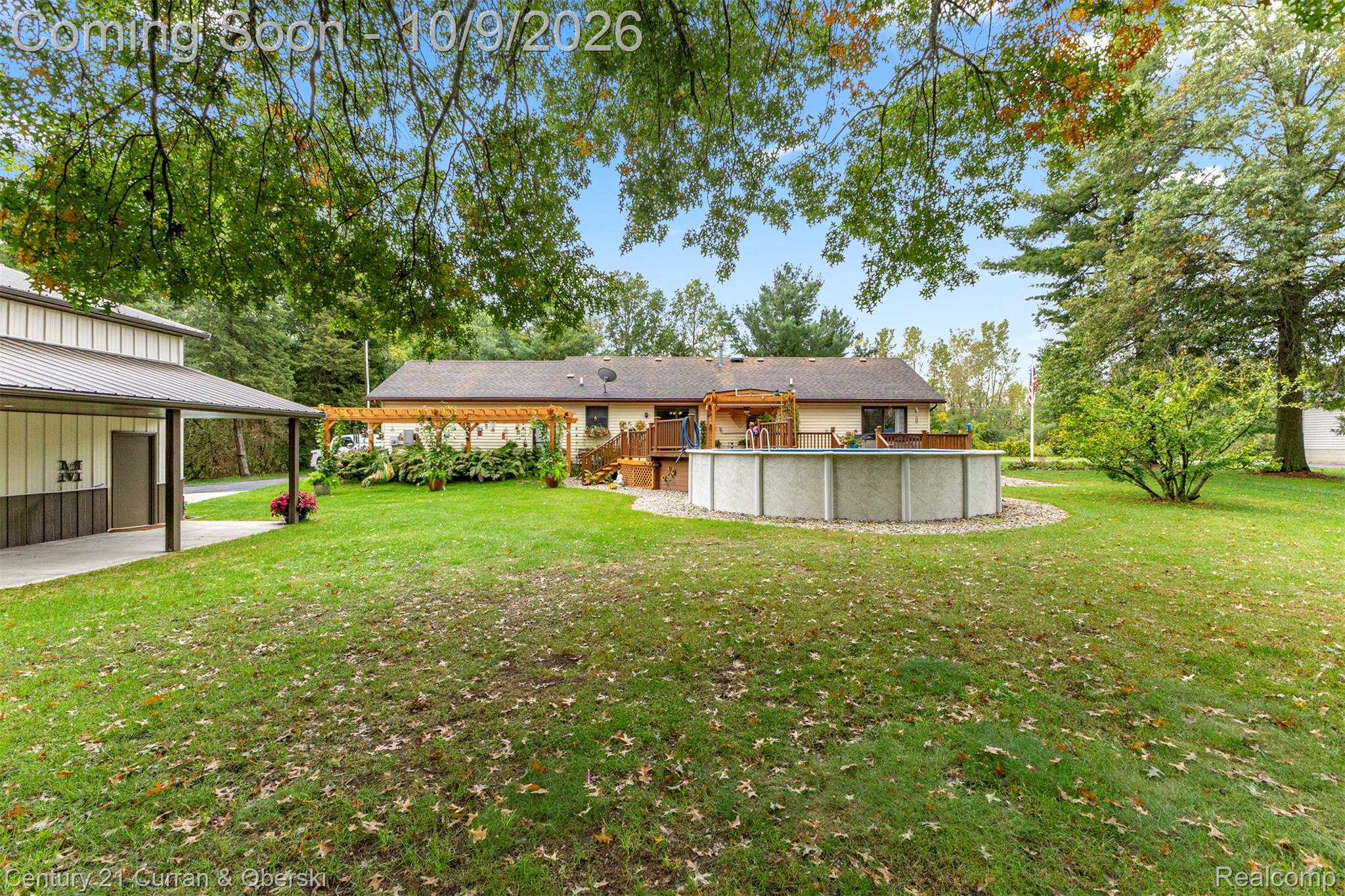 43040 Willis Road Belleville, MI 48111 - Photo 53 of 65 Expansive backyard featuring a manicured lawn, an above-ground pool, a wooden deck, and a detached building with a covered patio