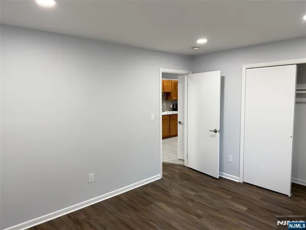 a view of an empty room with wooden floor and closet
