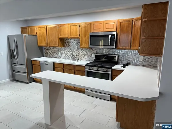 a kitchen with stainless steel appliances kitchen island granite countertop a refrigerator and a stove top oven