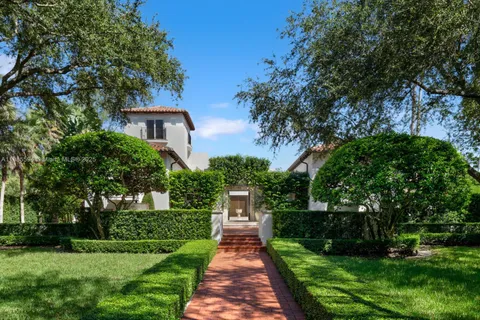 a front view of a house with a garden and trees