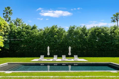 a view of a swimming pool with lawn chairs under an umbrella