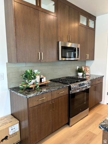2011 West 1150 South, Unit 1042 Payson, UT 84651 - Photo 16 of 39 Photos are of model home.Kitchen featuring wood-finish cabinetry with golden hardware, a stainless steel microwave, a stainless steel range with a built-in oven, stone countertops, and a green tile backsplash