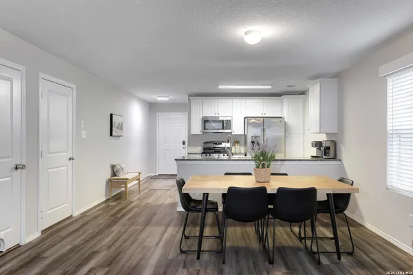 a kitchen with a dining table chairs and refrigerator
