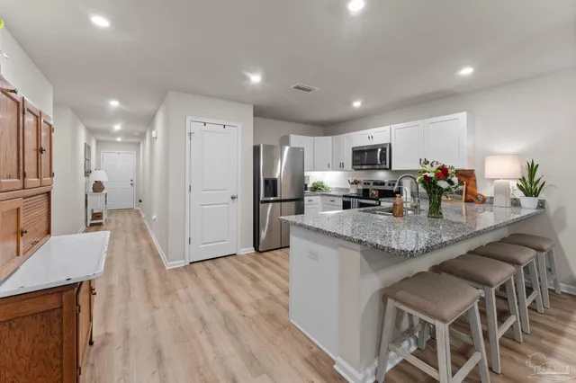 a kitchen with stainless steel appliances granite countertop a refrigerator a stove top oven a sink dishwasher and a refrigerator with wooden floor