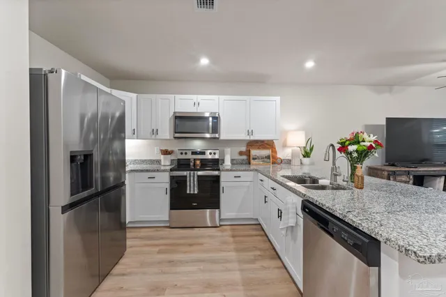 a kitchen with kitchen island granite countertop stainless steel appliances and sink
