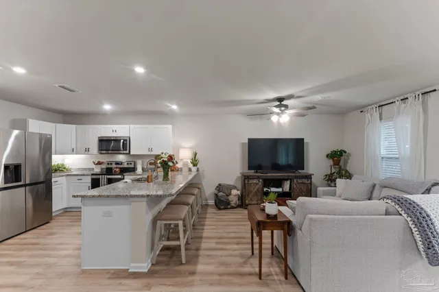 a living room with stainless steel appliances furniture and a flat screen tv