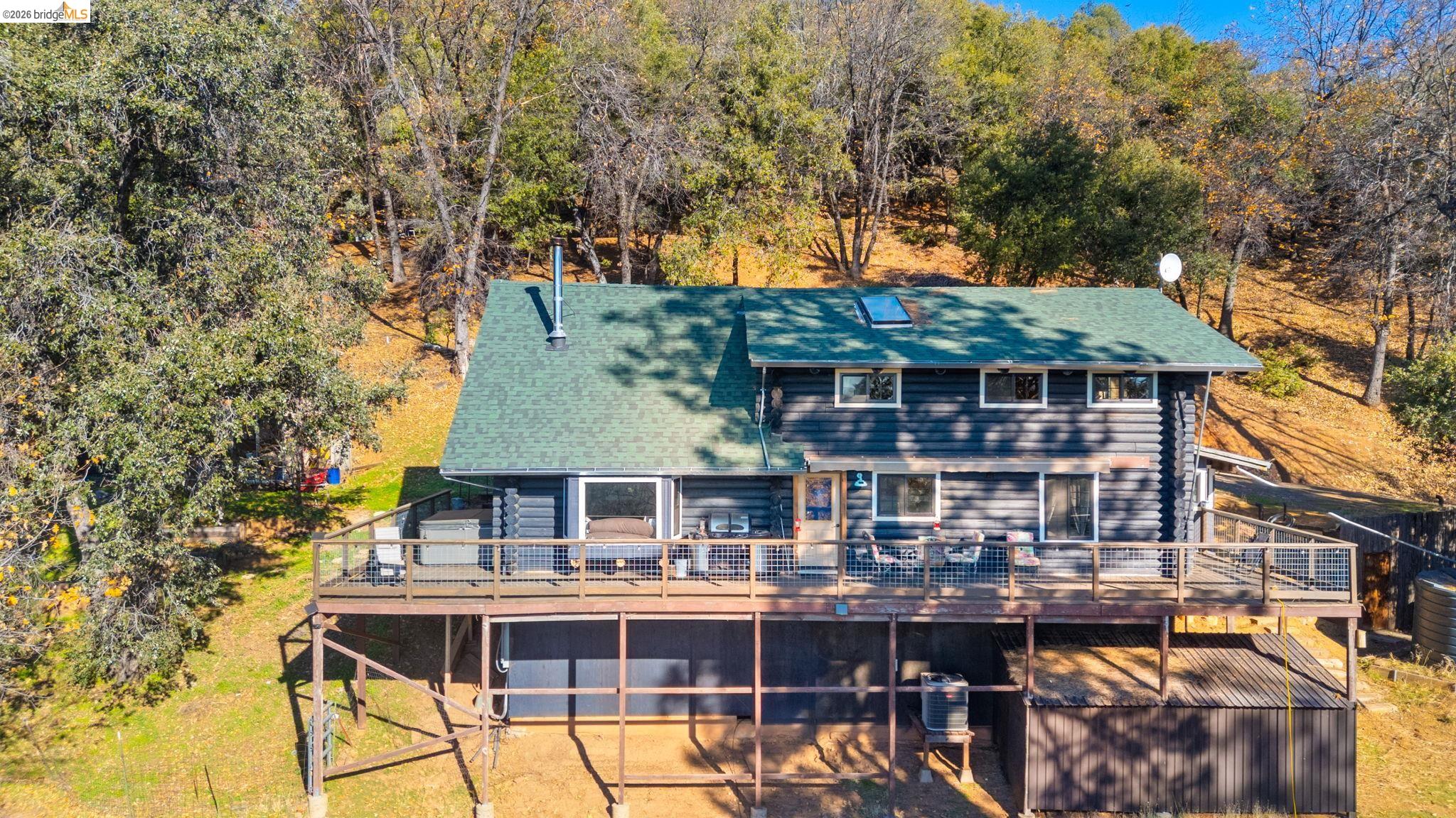 16144 Big Hill Road Sonora, CA 95370 - Photo 46 of 51 Multi-level log cabin-style residence featuring a dark-stained exterior, green shingle roof, and multiple windows