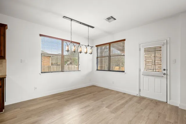 a view of an empty room with wooden floor and windows