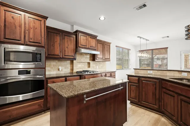 a kitchen with stainless steel appliances granite countertop a stove microwave and sink