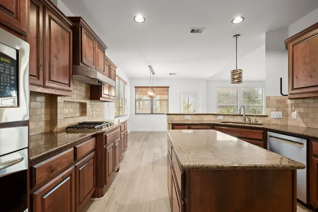 a kitchen with granite countertop stainless steel appliances and wooden cabinets