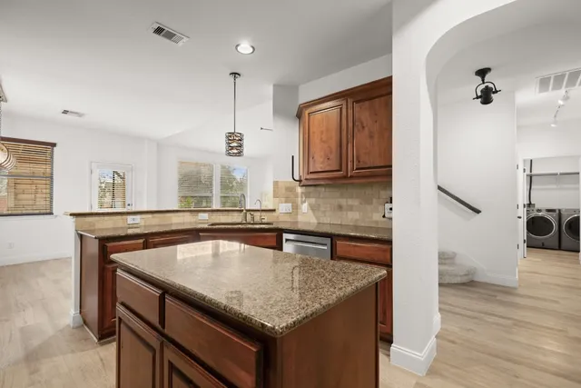 a kitchen with stainless steel appliances granite countertop a sink dishwasher a microwave oven and a dining table with wooden floor