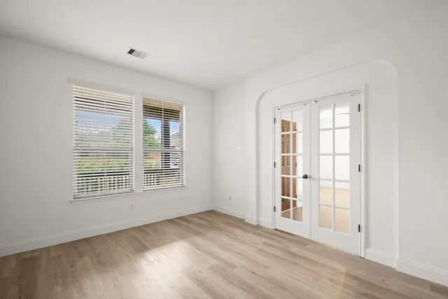 an empty room with wooden floor and windows