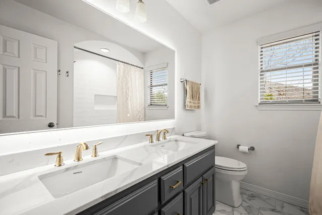 a bathroom with a granite countertop sink a toilet and a mirror