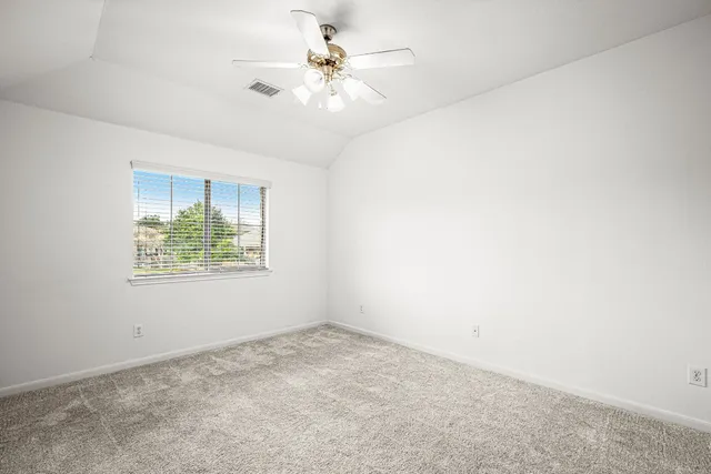 an empty room with windows and ceiling fan