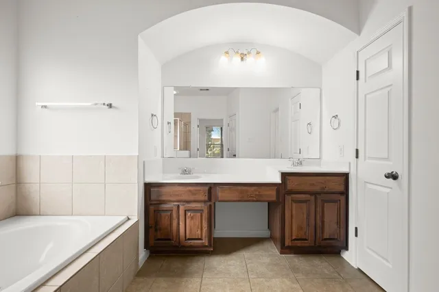 a spacious bathroom with a tub sink and mirror