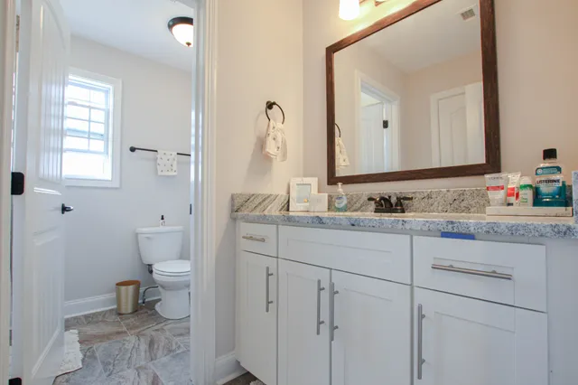 a bathroom with a granite countertop sink toilet and mirror