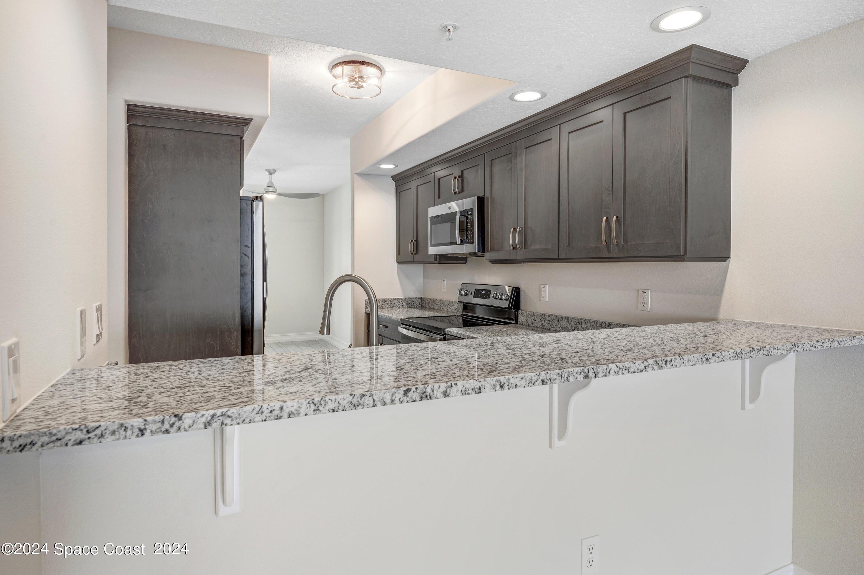 1805 Riverside Drive, Unit 606 Titusville, FL 32780 - Photo 11 of 40 a kitchen with stainless steel appliances granite countertop a sink a stove and a microwave oven