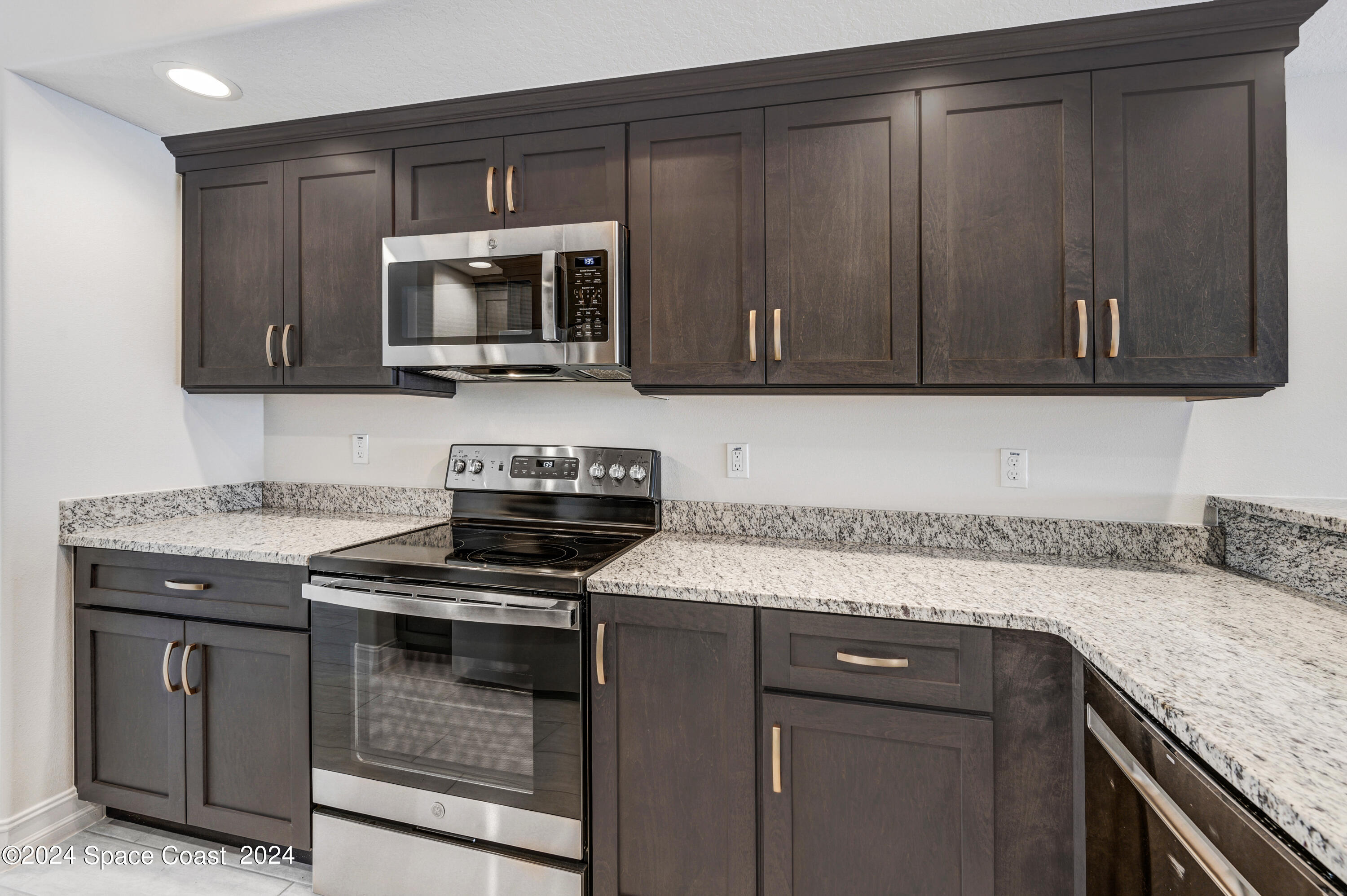 1805 Riverside Drive, Unit 606 Titusville, FL 32780 - Photo 12 of 40 a kitchen with granite countertop a sink dishwasher stove and microwave with wooden cabinets
