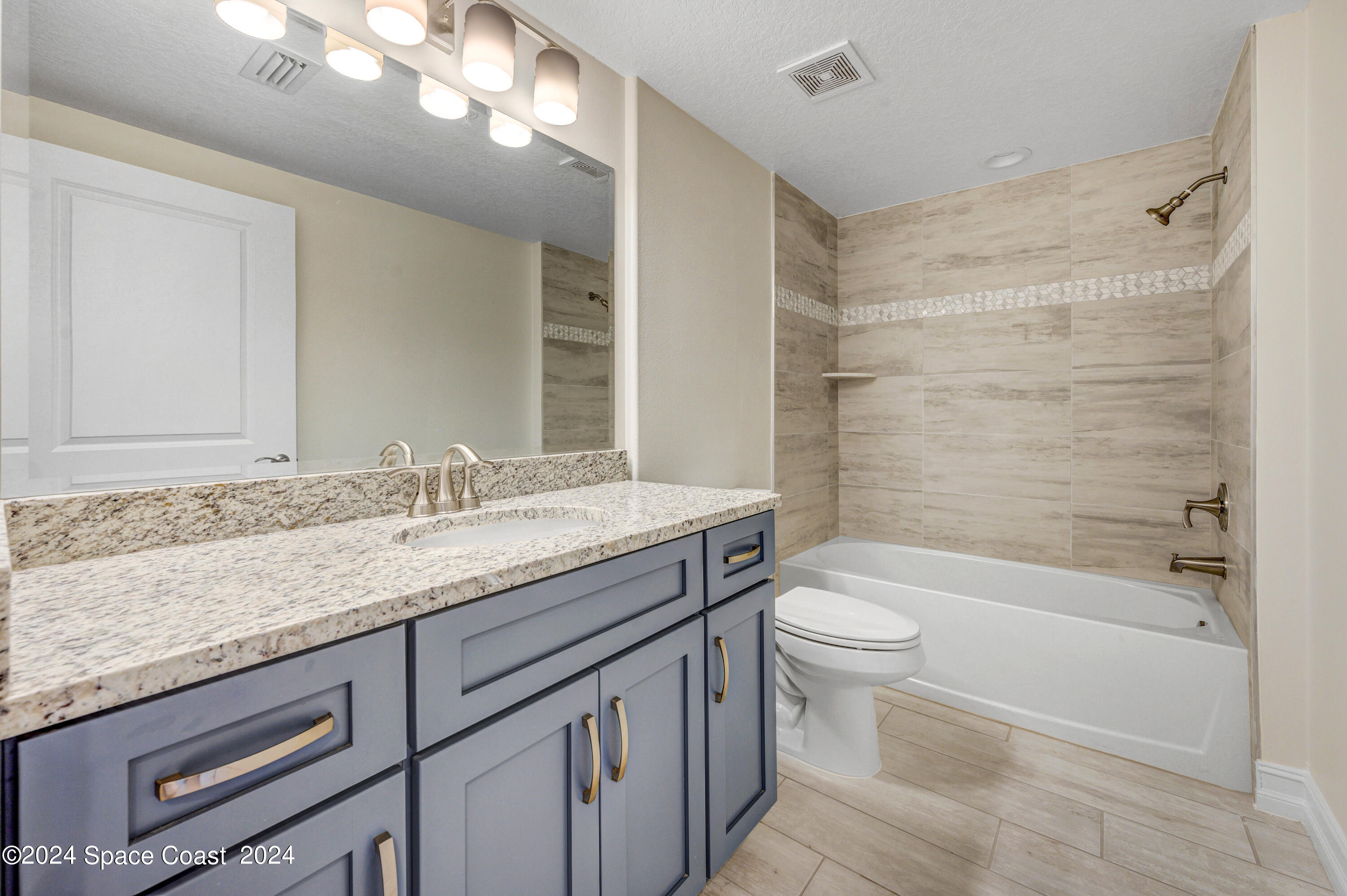1805 Riverside Drive, Unit 606 Titusville, FL 32780 - Photo 21 of 40 a bathroom with a granite countertop toilet a sink and a bathtub