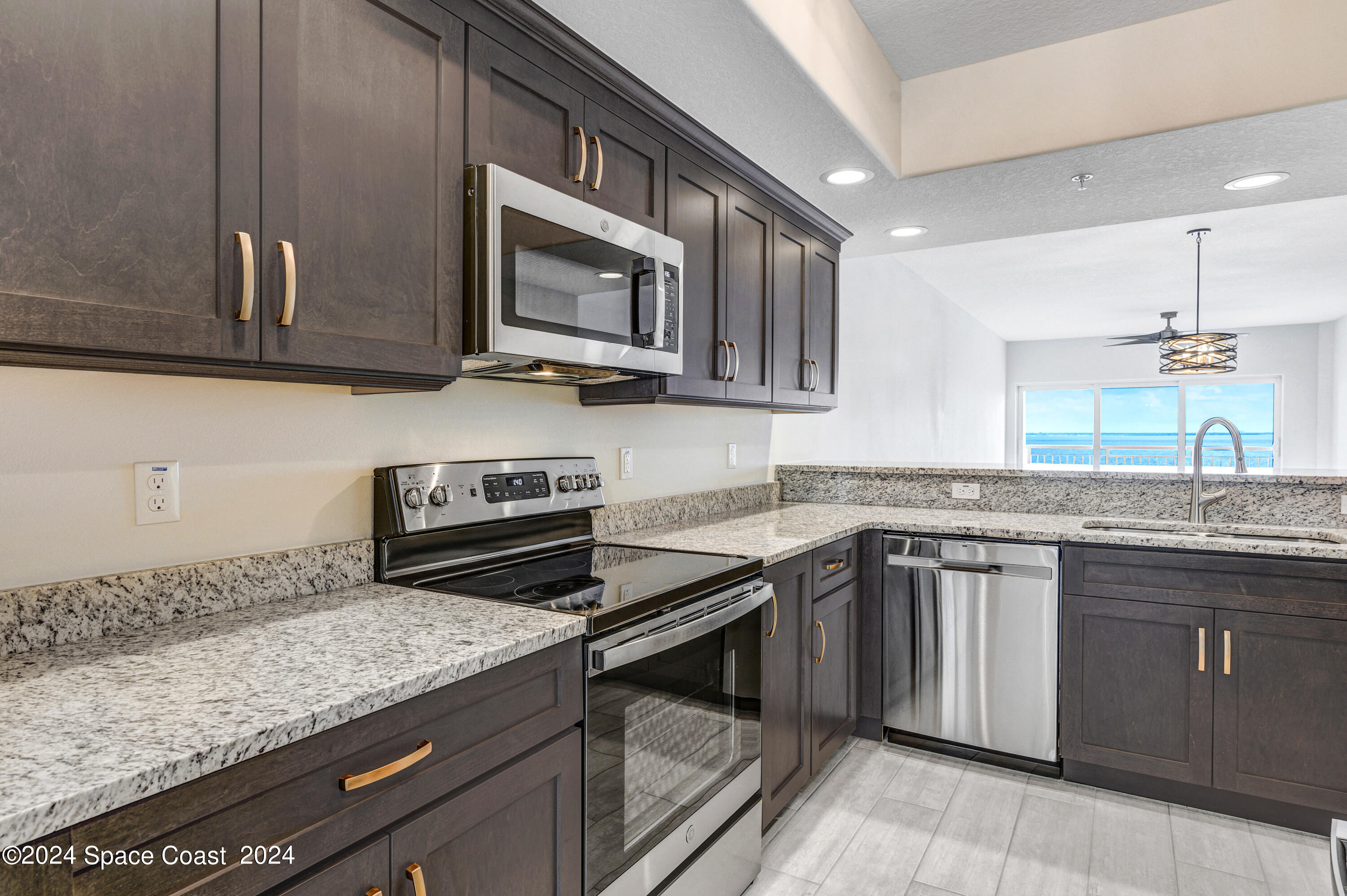 1805 Riverside Drive, Unit 606 Titusville, FL 32780 - Photo 8 of 40 a kitchen with stainless steel appliances granite countertop a sink stove and microwave