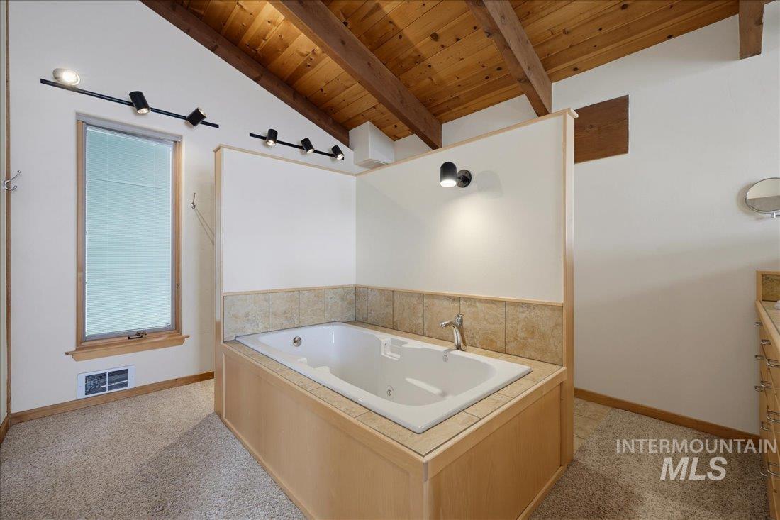 3800 Warren Wagon Road McCall, ID 83638 - Photo 21 of 50 Recessed tub with tiled surround, wood-finish paneling, and brushed nickel fixtures